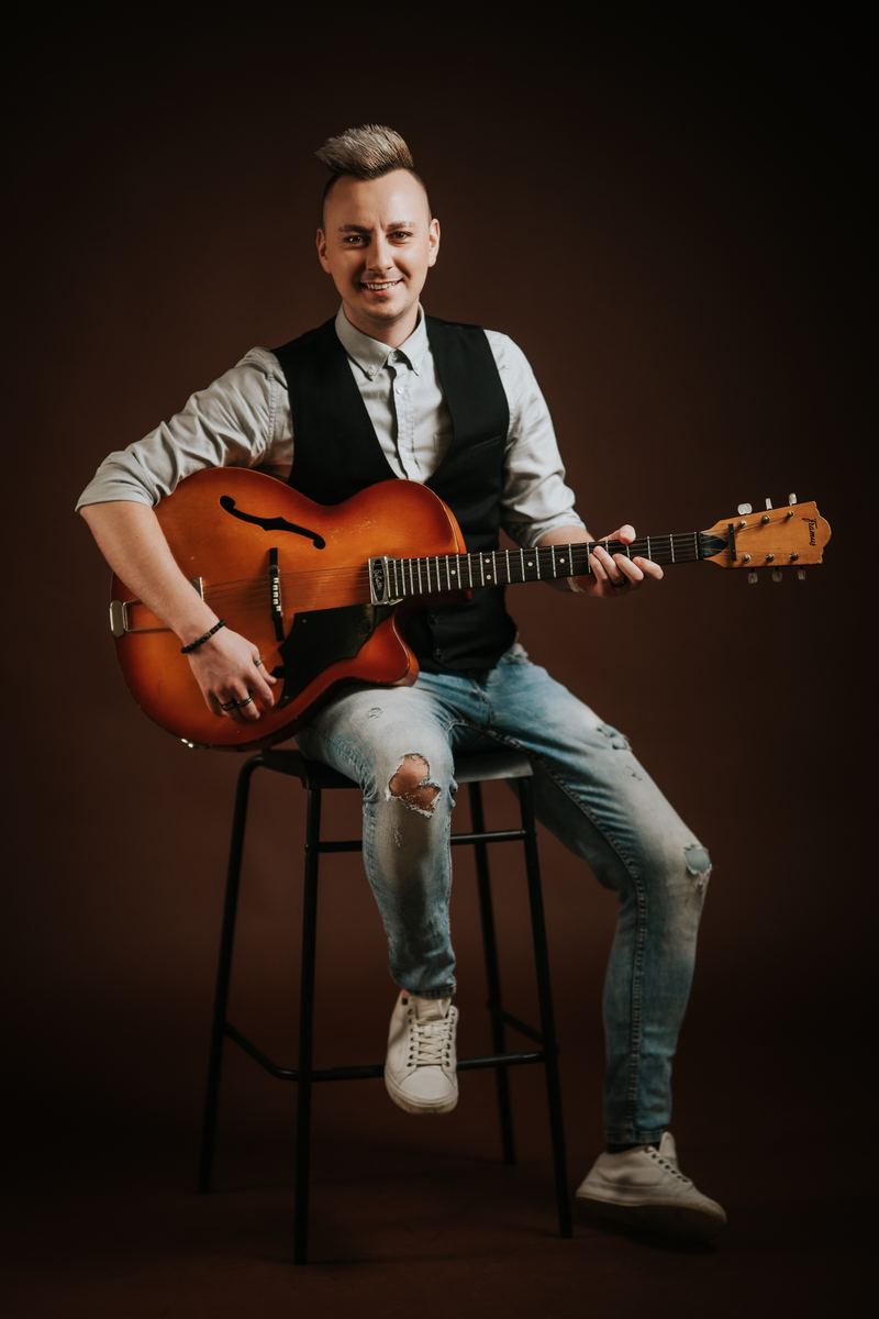 Sergej Vrhovnik s kitaro na barskem stolu