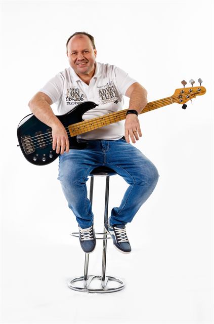 Marko Fijavž z bas kitaro na barskem stolu
